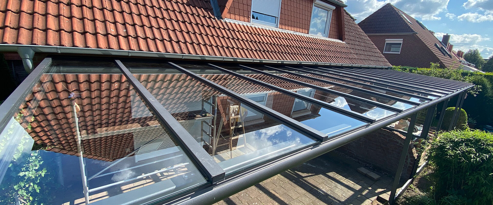 Ein Glasvordach vor einem Garten Ein Glasvordach vor einem Garten